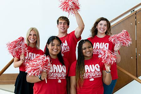Dual Enrollment students, in matching t-shirts, shake red and white pompoms in a group photo